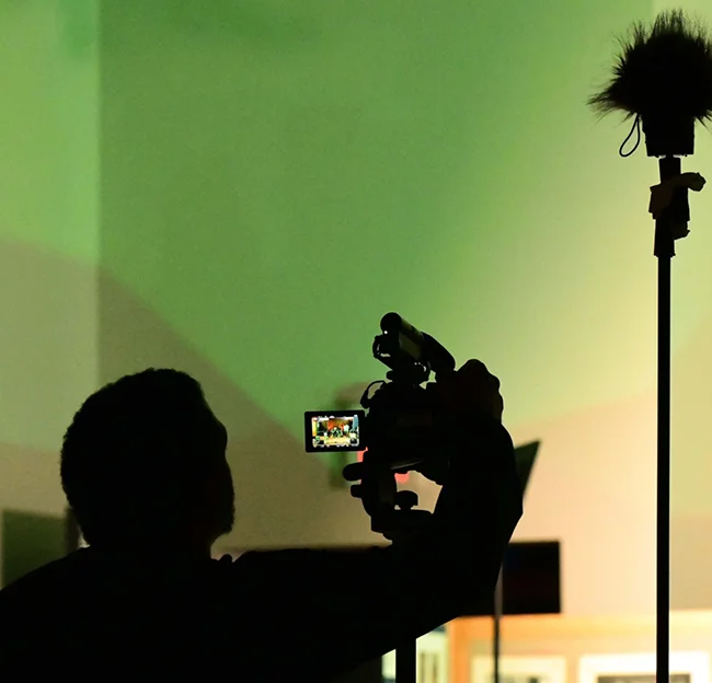person in silhouette with video camera and boom mic