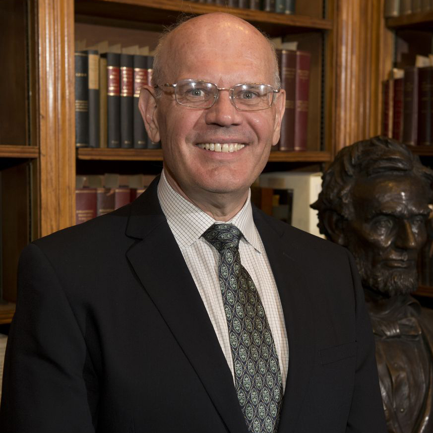 portrait of James Oaks; books in bookcase in background