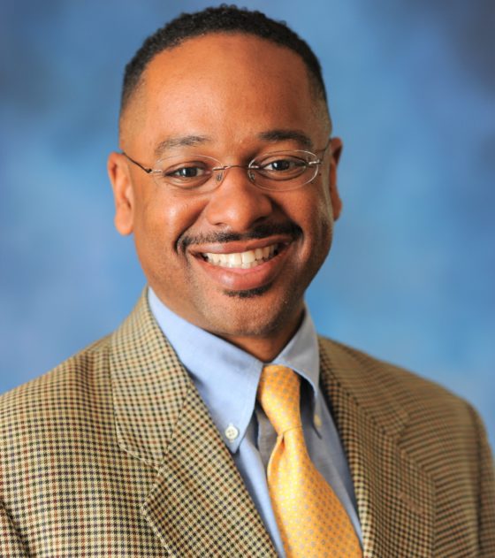 Smiling portrait of Rolando Herts wearing suit and tie