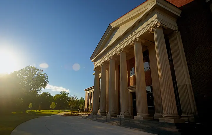 Outside of law school building with columns and bright sun flare
