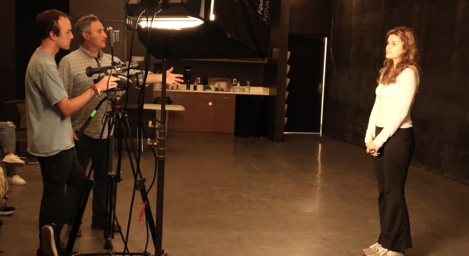 student standing in front of the camera while the acting professor gives instructions
