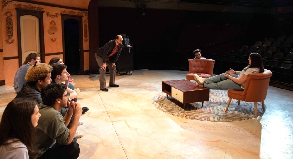 students and faculty member on stage while working on acting a scene