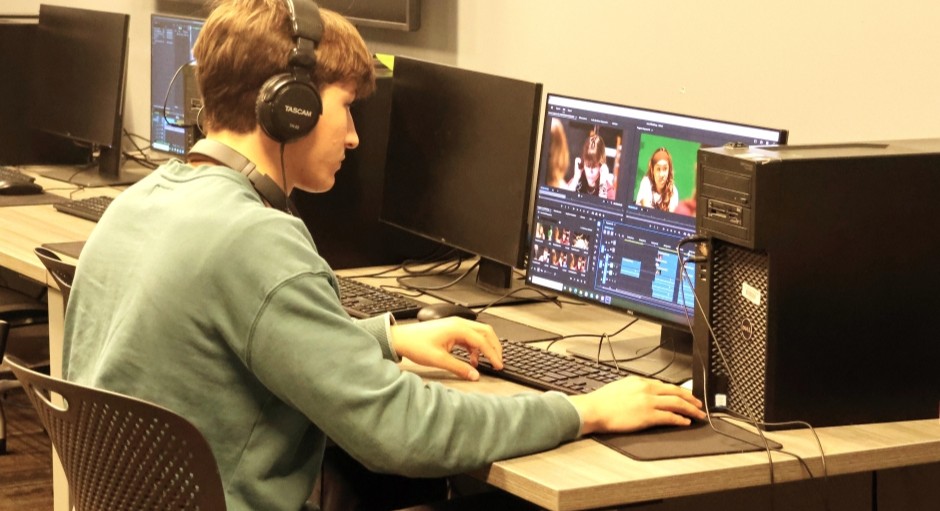 student sitting by himself working at an editing computer
