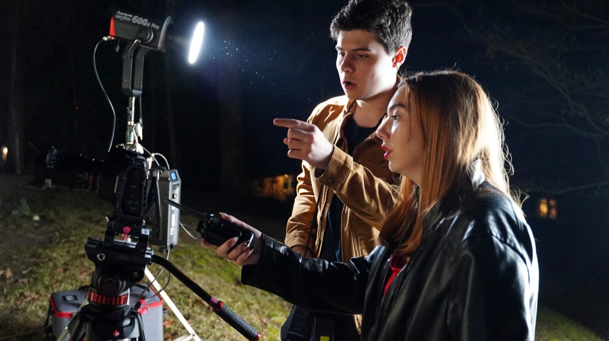 film shoot at night with student director and another student standing behind the camera