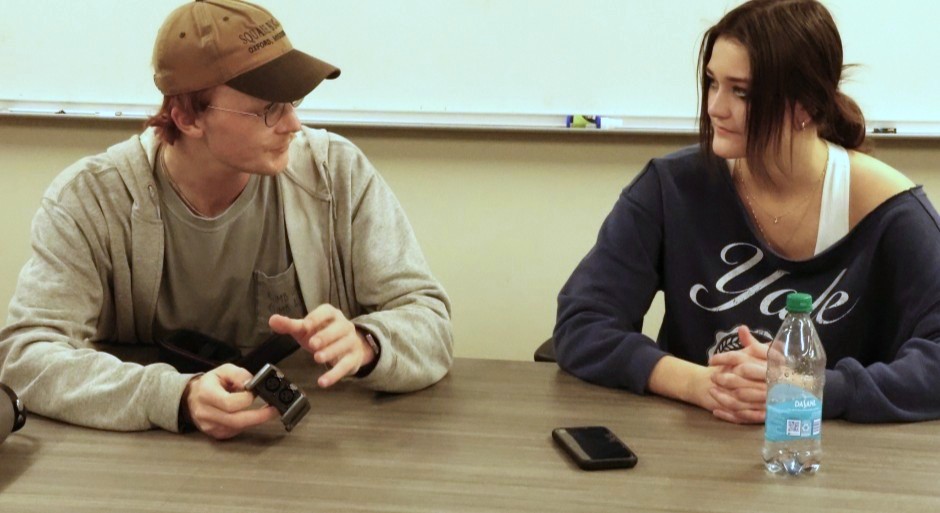 students seated at a table conferring over a script