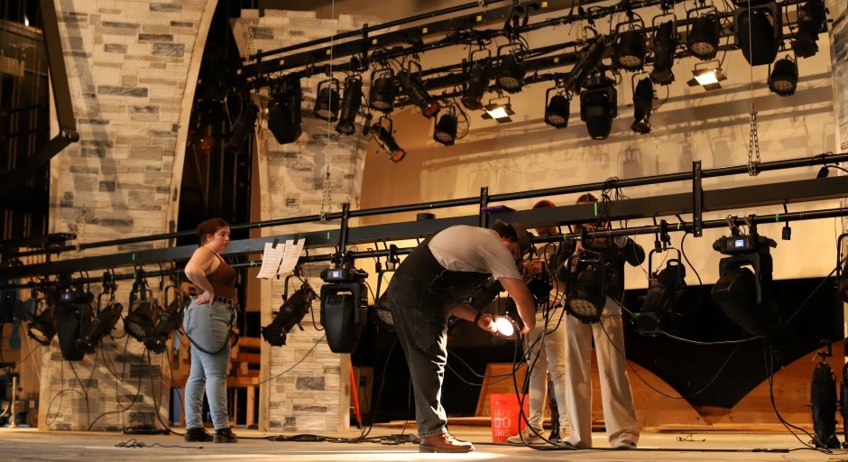 students loading lighting on poles on stage