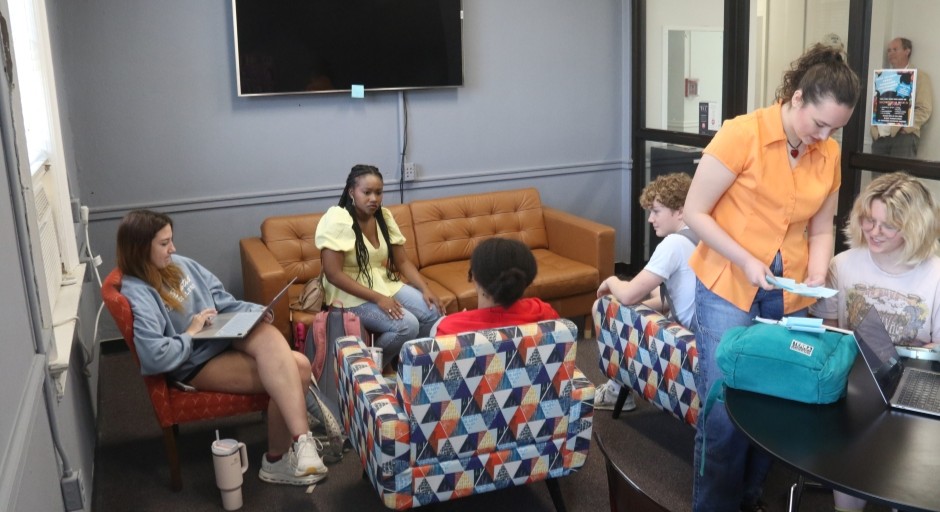 students seating in soft seating and at table in a lounge