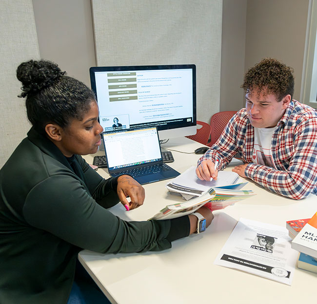 two people sitting at desk talking