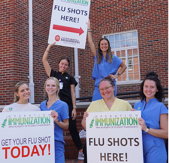 Students holding signs for the Operation Immunization flu shot clinic