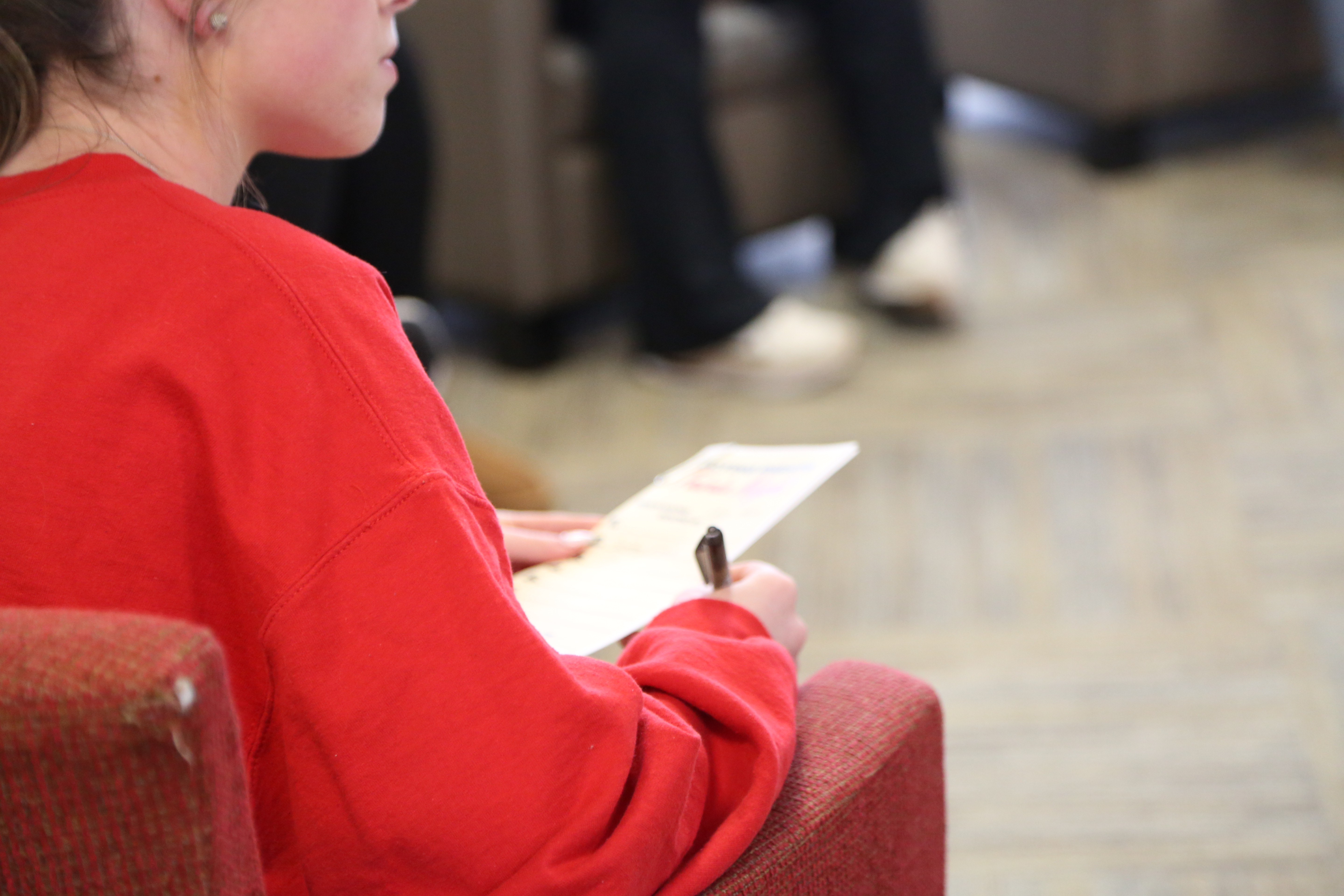 a person sitting in a chair with their back to the camera holding a piece of paper