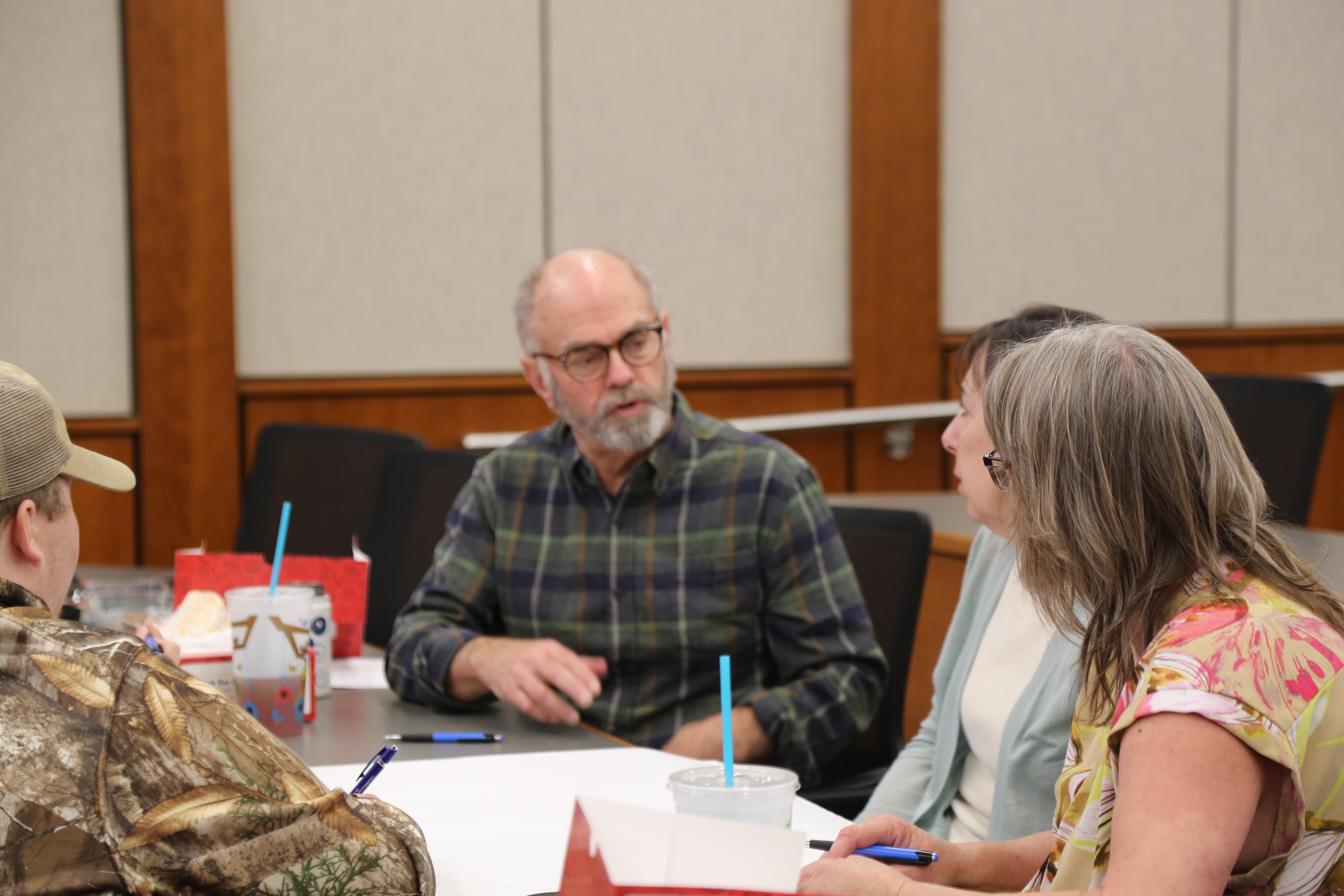 a grouped of four people siting around a table having a conversation