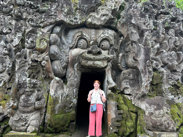 student in front of cave