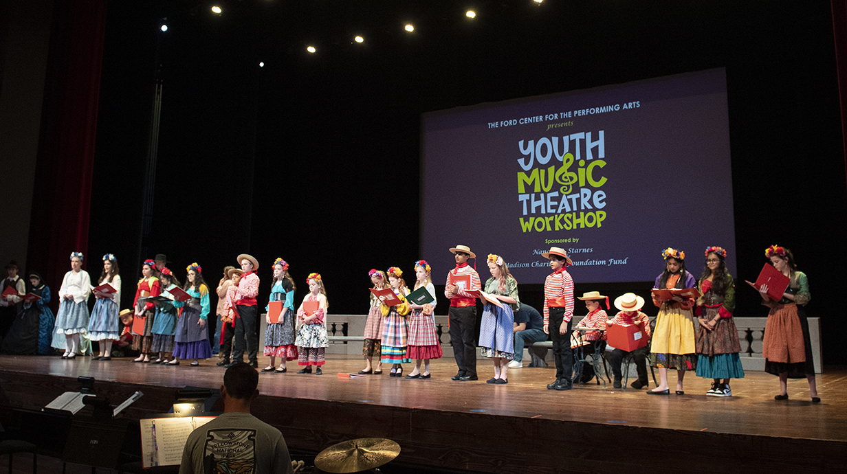 Children in costume line up on the stage at the Ford Center Youth Music Theatre Workshop