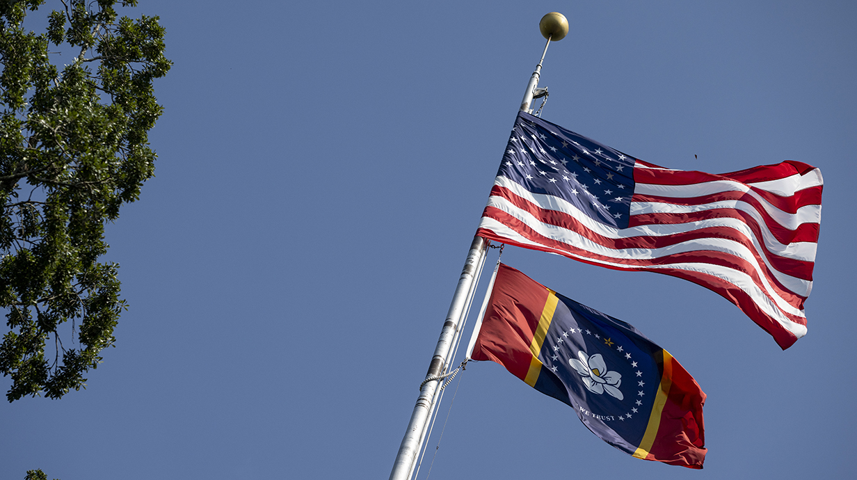 The American flag and Mississippi state flag flying on a flag pole on campus