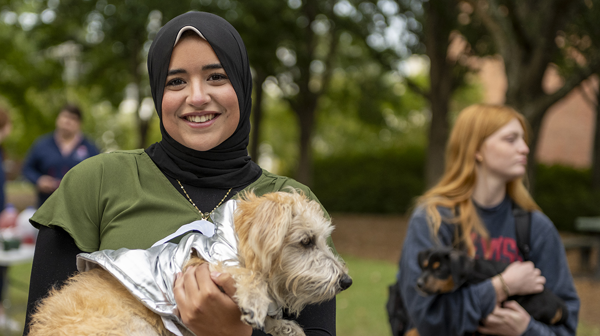 Ole Miss Freshman in Pharmacy, Mennah Ibrahim from Oxford, Miss., poses for a picture while holding one of the dogs at the Ole Miss Career Center’s Canines, Careers, and Cookies event on the Martindale-Cole Lawn at the University of Mississippi.