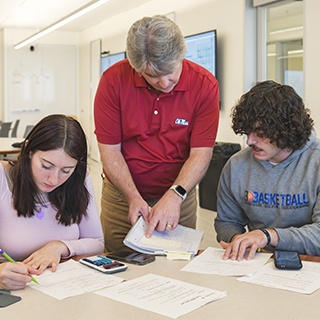 Instructor assists two students with coursework during a STEM class activity.