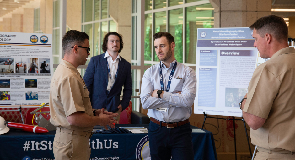 Three people speaking in front of a research poster.