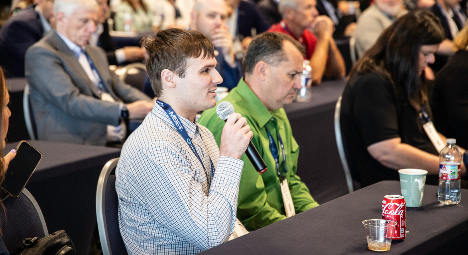 A man holding a microphone asks a question.