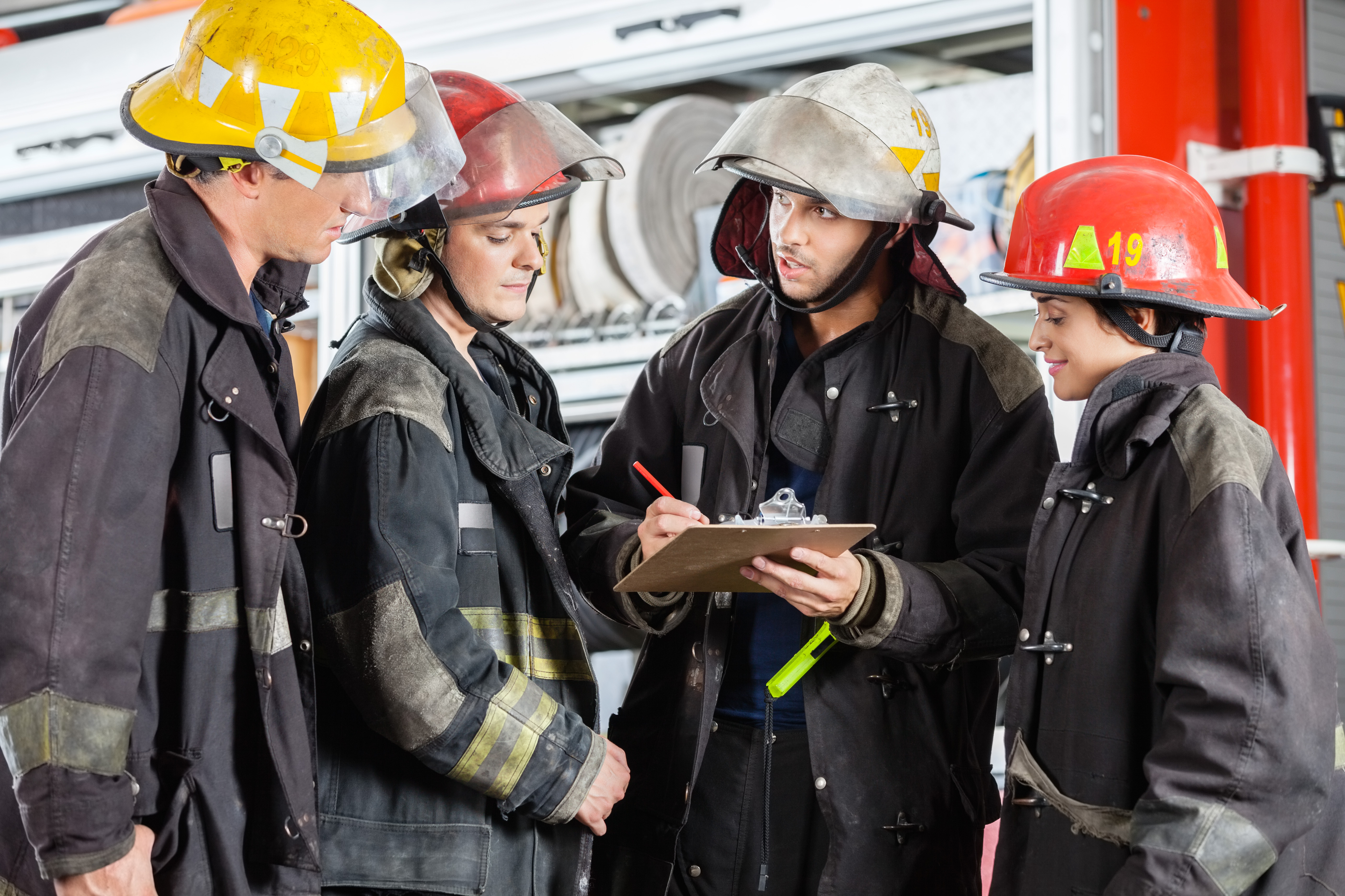 fire fighters in a circle looking at a clip board
