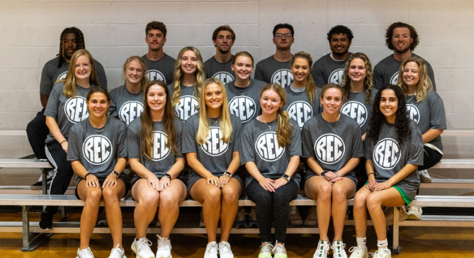 Fitness student employees sitting on bleachers.