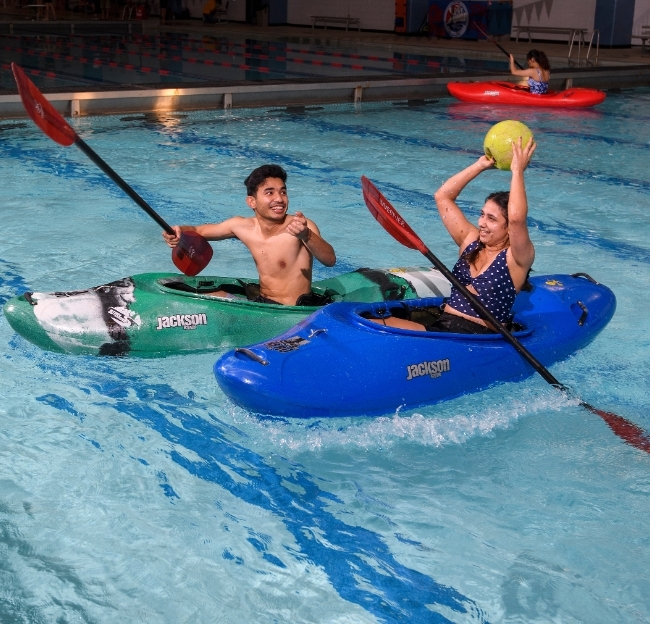Two students playing kayak water polo.