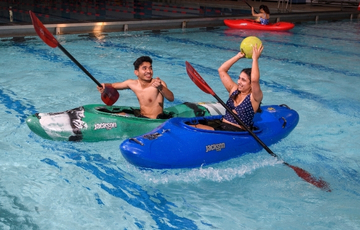Two people playing kayak water polo in the pool