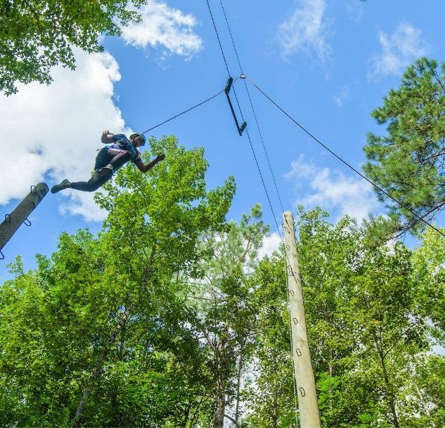 Individual jumping off the power pole at the challenge course.