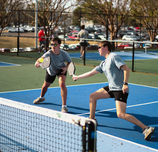 Two students playing pickleball outdoors