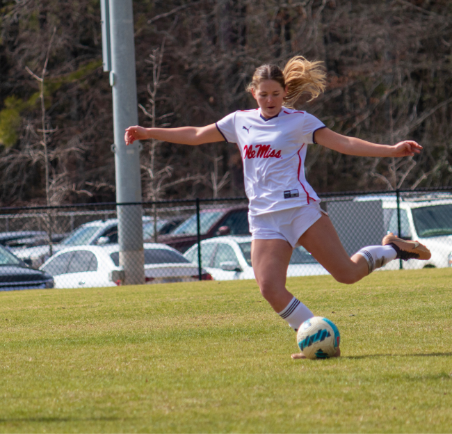 Women's club soccer player kicking a soccer ball
