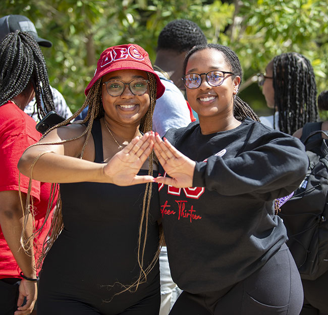 Two NPHC sorority members hold up the delta hand signal