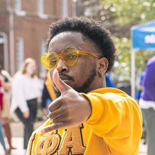 AN NPHC fraternity member holds up his fraternity hand sign