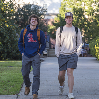 Two IFC members walk to class and smile at the camera