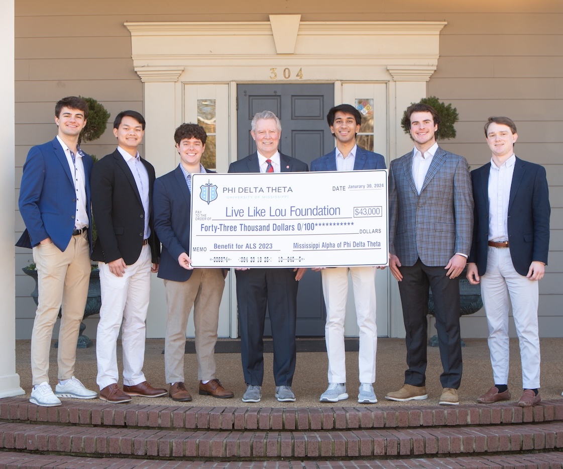 Phi Delta fraternity members and Chancellor Glenn Boyce with a commemorative check