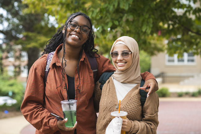 Two students smiling with drinks
