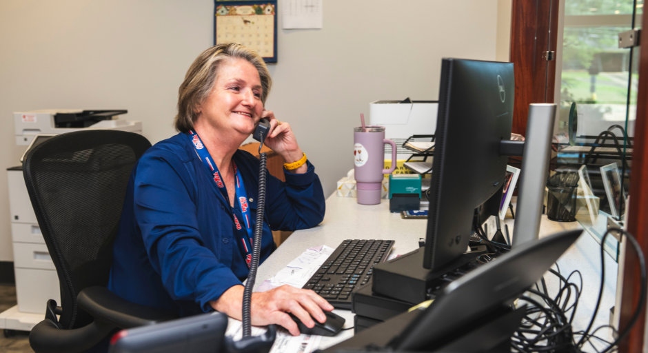 Employee answers phone at reception desk.