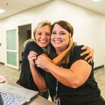 Two staff members embracing and smiling.