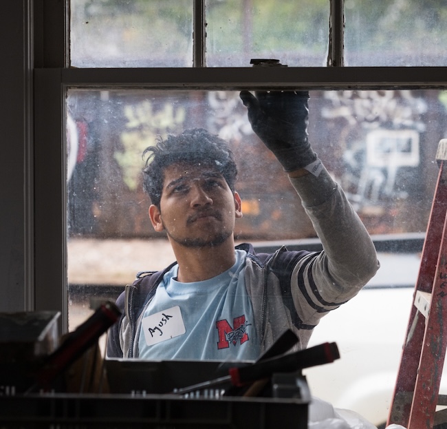 A student repairs a window during an M Partner project.