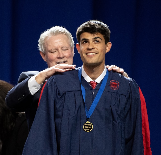Chancellor Boyce presents a student with his Honors College medal at commissioning. 