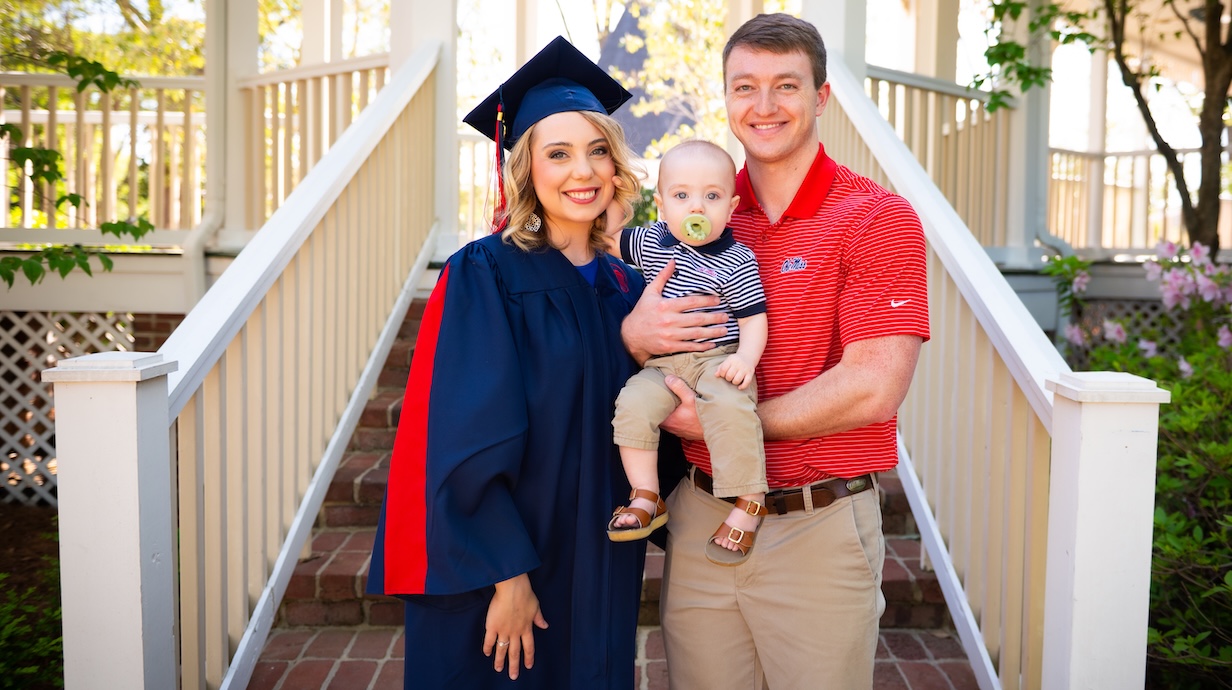 A family poses with their young child at graduation.