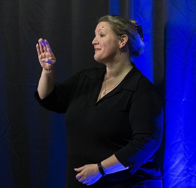 An ASL interpreter interprets a speech at graduation.