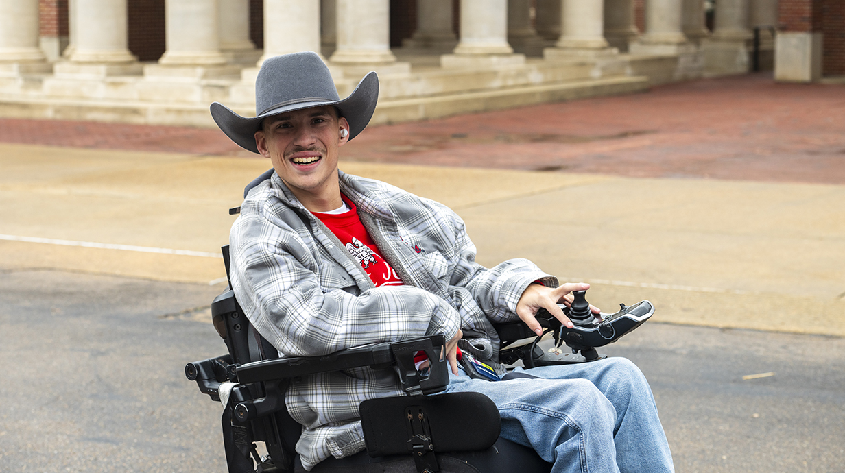 A student wearing a cowboy hat smiles