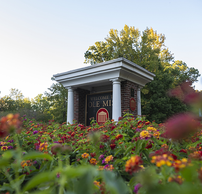 The "Welcome to Ole Miss" sign surrounded by colorful red, orange, yellow, and purple flowers.