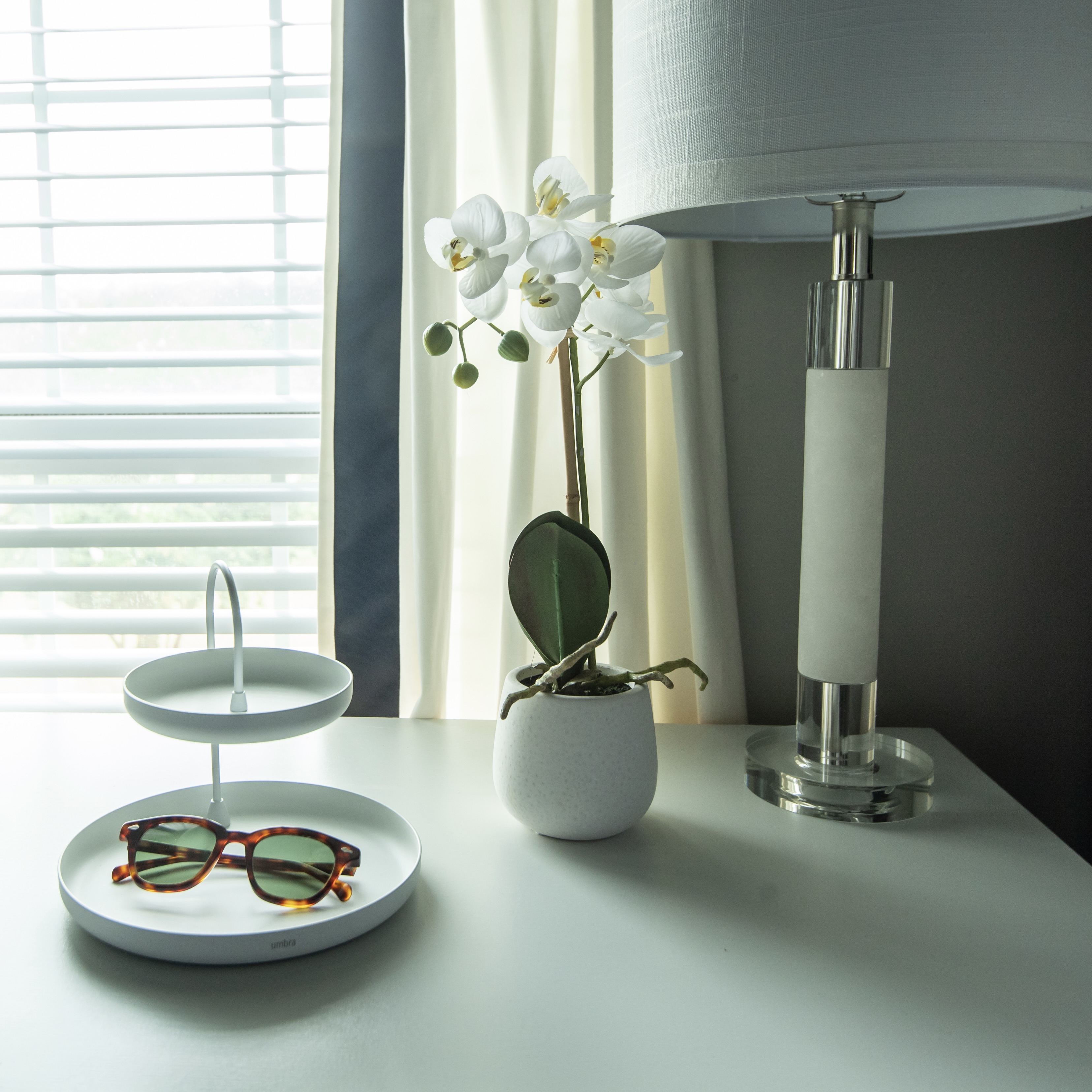 Sunglasses sitting on table next to a lamp and window