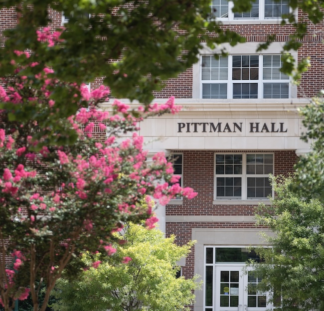 Photo of the outside of Pittman Hall with pink flowers in bloom. 