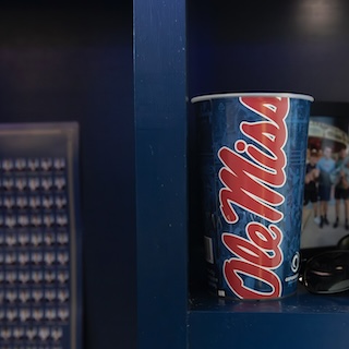 Cup with "Ole Miss" written down the side, sitting on a shelf