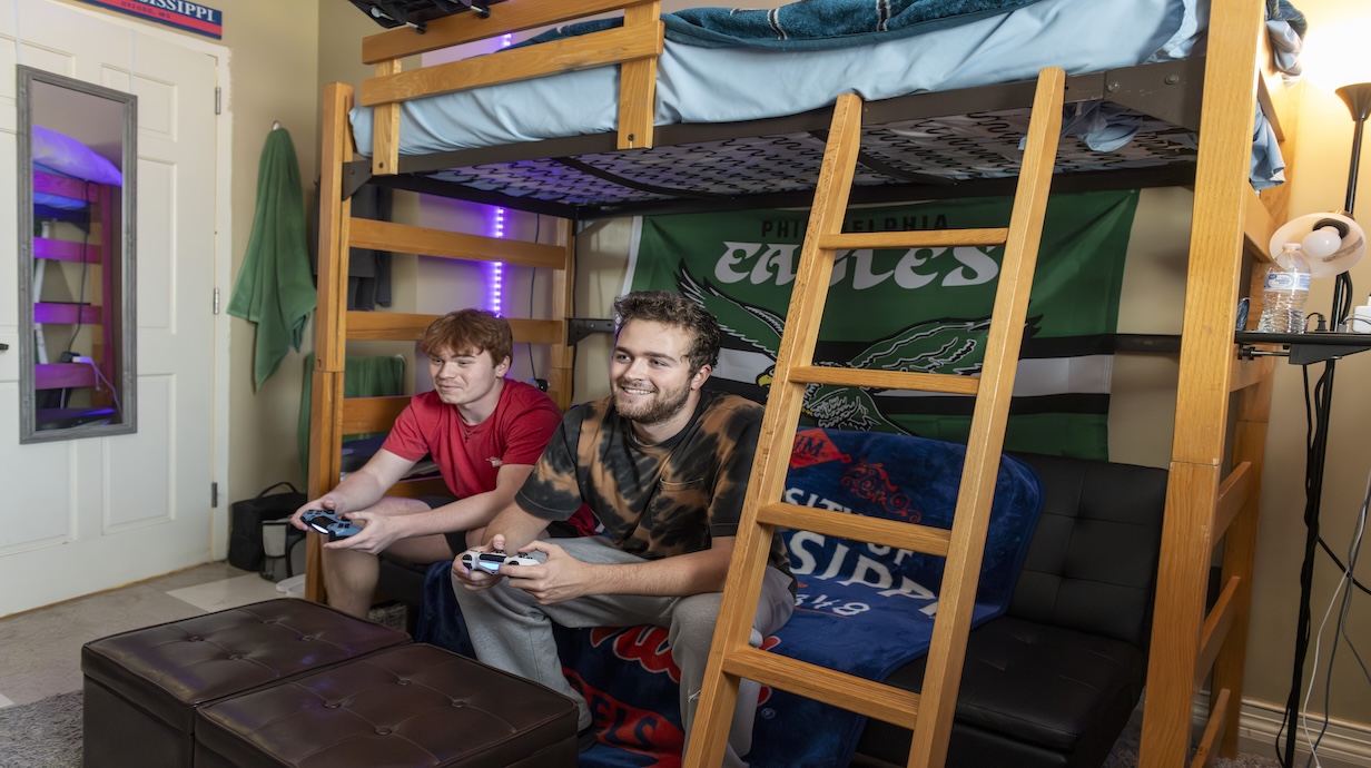 Two men sitting on a couch holding controllers playing video games