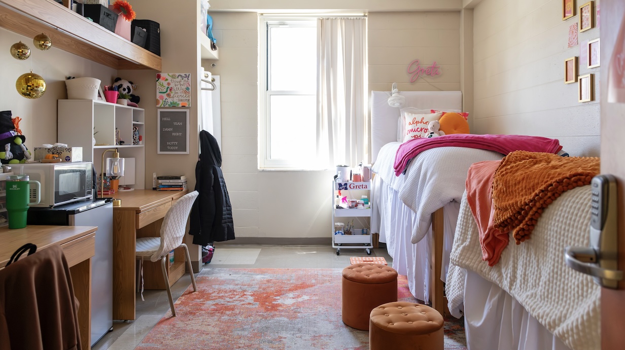 photo of a desk, window and bed with pink and gold accents