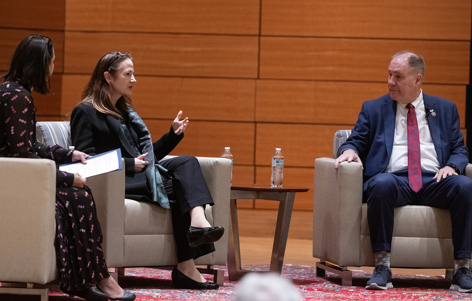 Three leaders conversing on stage at a seminar