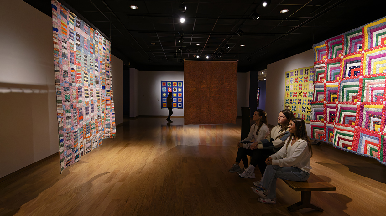 image of students observing a quilt on display at the university museum