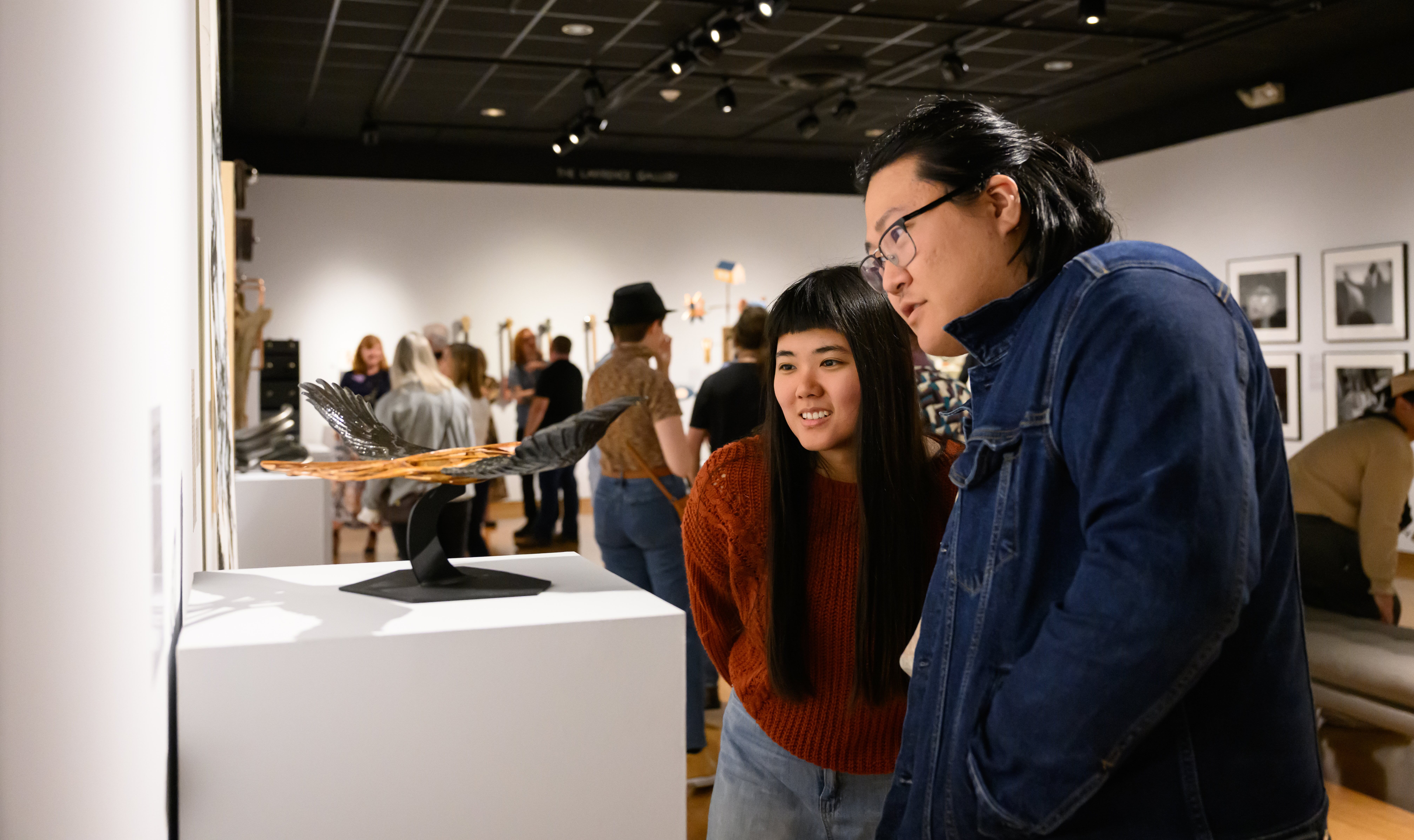 people looking at bird sculpture